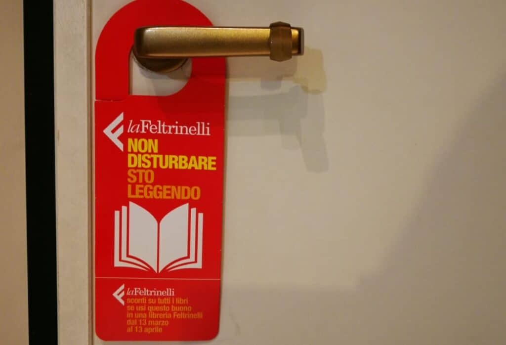 Cartello appeso alla porta "Non disturbare, sto leggendo"