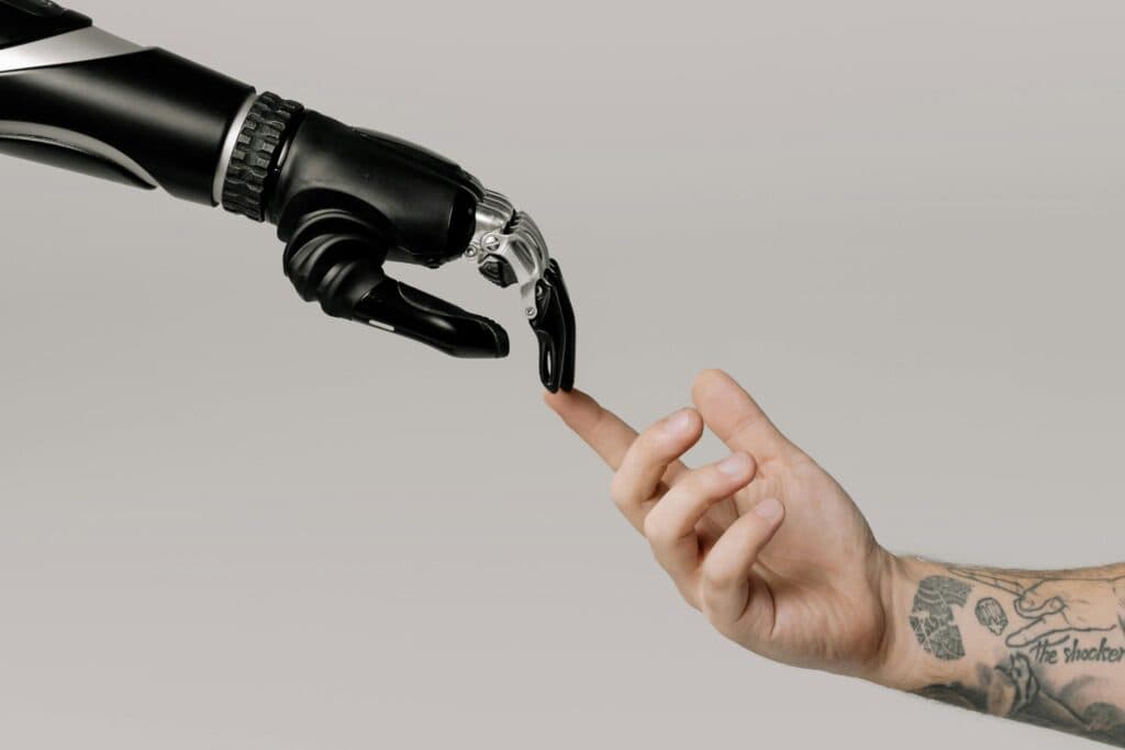mano robotica che tocca una mano umana, come l'affresco di Michelangelo